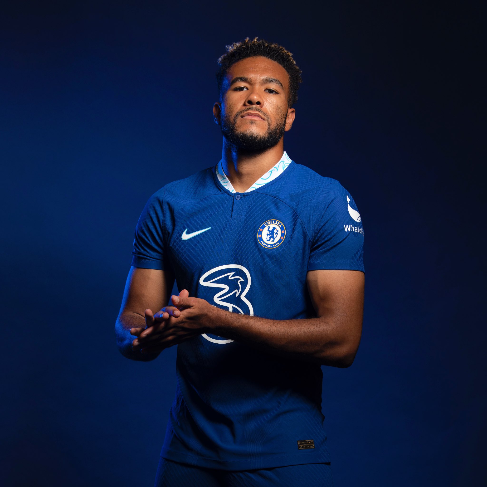 Рис Джеймс в домашней форме Chelsea 2022/23 на тёмно-синем фоне: бирюзовый воротник, Three на груди и WhaleFin на рукаве.